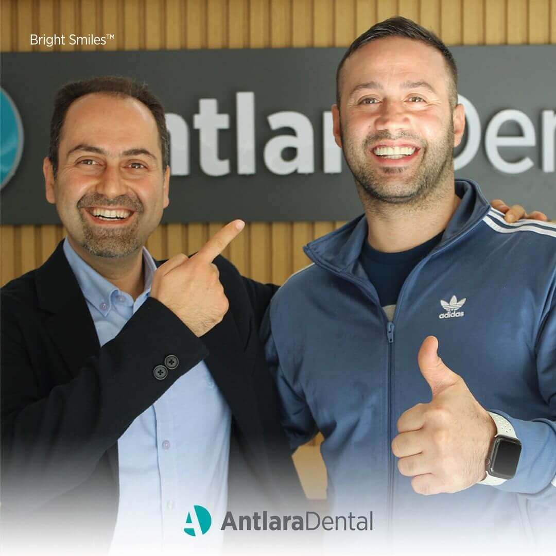 два человека стоят, у одного из них установлен зубной имплантат в клинике Antlara Dental в Турции