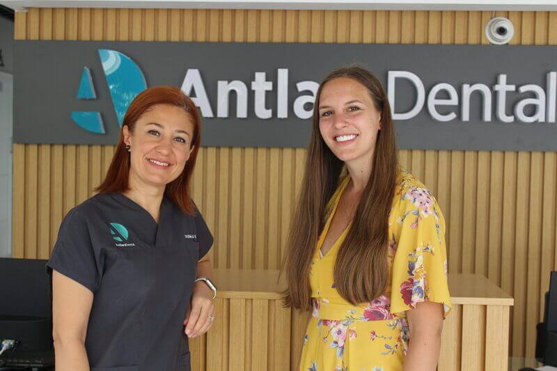 two women giving pose in front of dental clininc logo