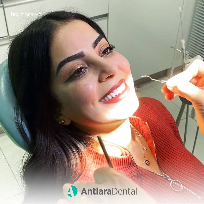 patient sit in the dental clinic room and dentist examine her mouth with a dental instrument.