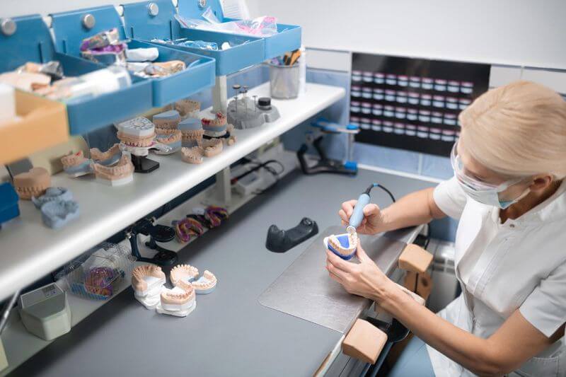 A dentist designing teeth for dental implant with dental instruments in her hands.